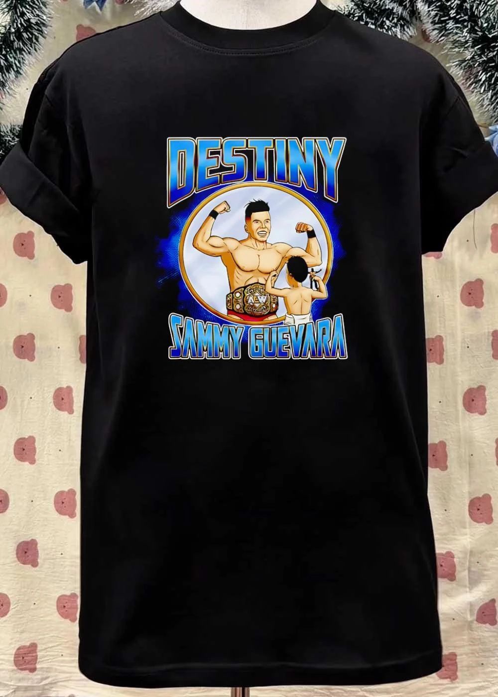 Destiny Sammy Guevara flexing with baby holding wrestling action figure shirt