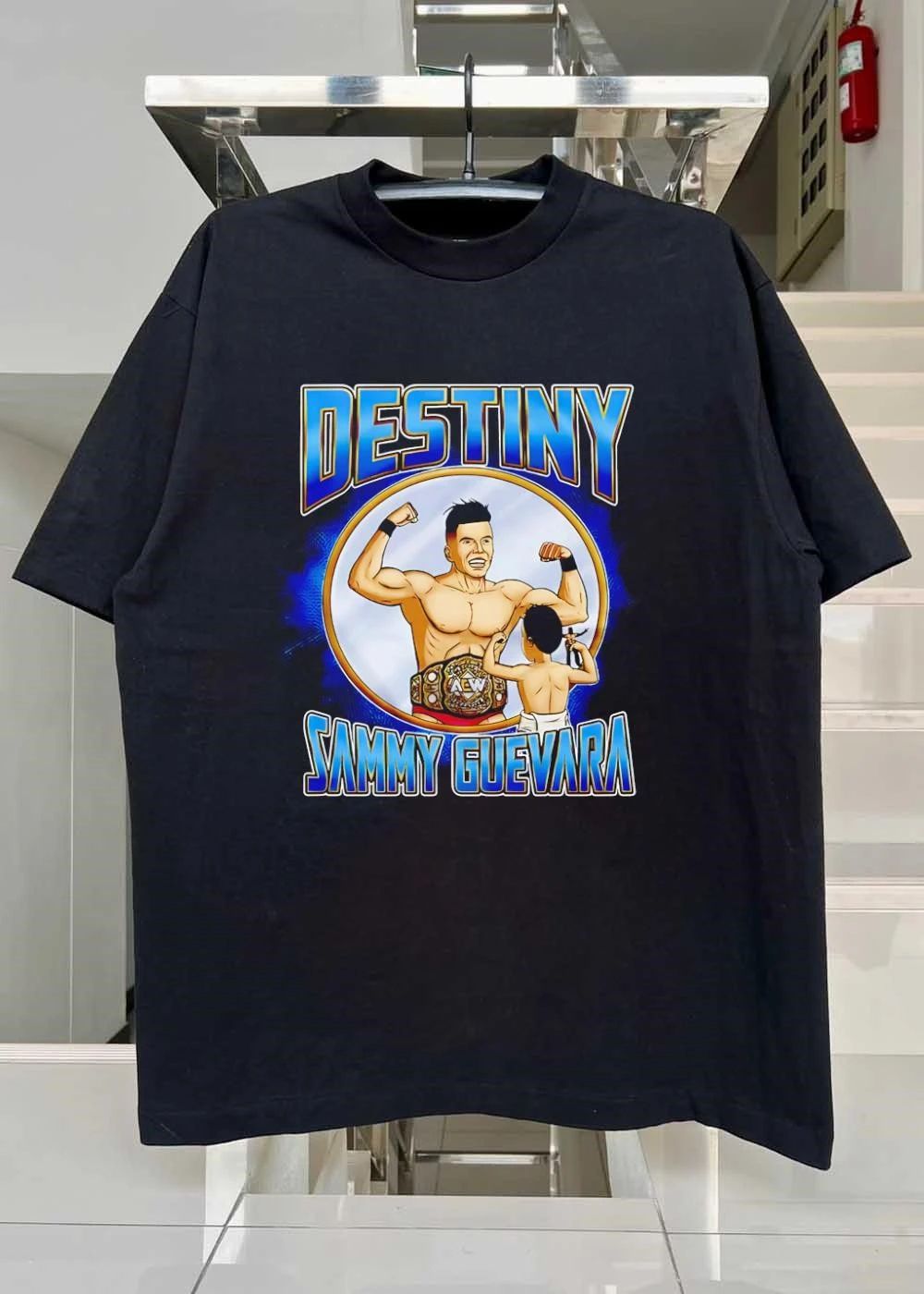 Destiny Sammy Guevara flexing with baby holding wrestling action figure shirt